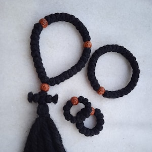 Puede incluir: Tres cuerdas de oración negras con cuentas de madera. La cuerda más grande tiene un borla.