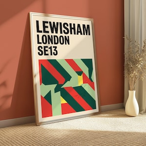Könnte beinhalten: Ein gerahmter rechteckiger Wandkunstdruck mit dem schwarzen Text LEWISHAM LONDON SE13 im oberen Bereich. Unter dem Text befindet sich ein geometrisches Muster aus diagonalen Streifen und Formen in Dunkelgrün, Hellgrün, Rot und Gelb.