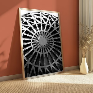 May include: A framed black and white wall art print featuring a geometric architectural structure. The image displays a circular pattern of intersecting metal beams and rivets radiating from a central point, creating a complex radial design.