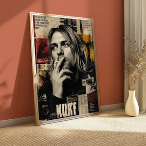 Peut inclure: Une affiche murale encadrée rectangulaire présentant un portrait en noir et blanc de Kurt Cobain fumant. Le fond de style collage comprend des accents rouges et jaunes, des coupures de presse et le texte "I'd rather be hated for who I am, than loved for who I am not" et "KURT".