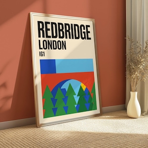 May include: A framed wall art print featuring the text REDBRIDGE LONDON IG1 in bold black letters at the top. Below the text is a geometric illustration with a light blue rectangle, a red arch, and a series of green triangular pine trees.