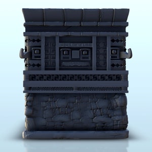 May include: A dark gray stone structure with intricate carvings and a stone base. The structure has a rectangular shape and a flat top. The carvings on the structure are in a geometric pattern.