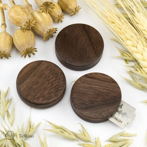 Könnte beinhalten: Drei runde Holzhalter mit einer dunkelbraunen Holzmaserung. Die Halter sind aus Walnussholz gefertigt und eignen sich perfekt zum Aufbewahren von kleinen Gegenständen wie Schmuck oder Schlüssel.