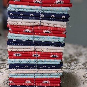 May include: A stack of fabric squares in red, white, and blue with various patterns, including polka dots, stripes, and geometric designs.