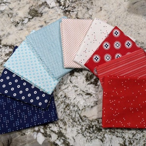 May include: A collection of ten fabric squares in various red, white, and blue patterns. The fabrics feature polka dots, stripes, and geometric designs.