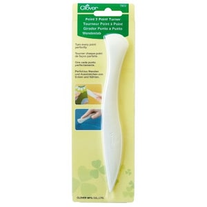 May include: White plastic Point 2 Point Turner tool for turning corners and seams perfectly. The packaging features green clover leaves and the text "Clover 7805 Point 2 Point Turner Tourneur Point à Point Girador Punto a Punto Wendestab Turn every point perfectly Toumer chaque point de façon parfaite Gare cada punto perfectamente Perfektus Wenden und Ausstreichen on Ecken und Nähien. CLOVER MFG. CO., LTD"