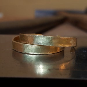 May include: Two gold-toned metal bangles with a hammered texture.