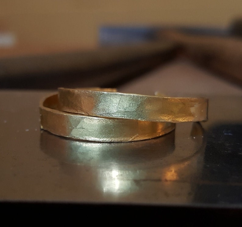 May include: Two gold-toned metal bangles with a hammered texture.