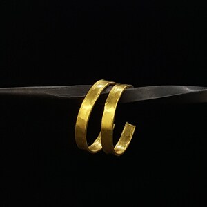 May include: A pair of gold hoop earrings with a hammered texture.