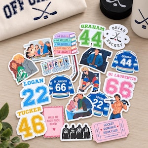 May include: A collection of vinyl stickers featuring hockey-themed illustrations, book titles, and player jerseys with numbers. The stickers include text like Off Campus, Graham 44, Logan 22, Tucker 46, and Hockey Romance Book Club, arranged near a tote bag and a hockey puck.