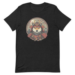 May include: Dark gray t-shirt featuring a Shiba Inu dog in samurai armor. The dog is inside a circular design with a Japanese landscape background. The samurai dog is wearing a red helmet and armor, holding a sword.