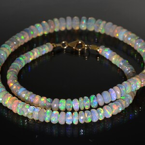 May include: A double strand necklace made of iridescent opal beads. The necklace is made of small, round beads that are strung together on a gold chain.