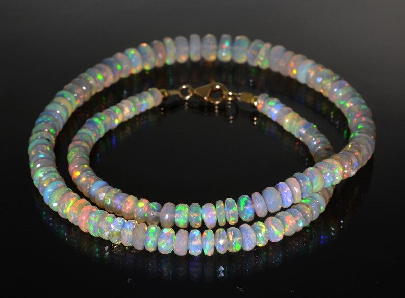 May include: A double strand necklace made of iridescent opal beads. The necklace is made of small, round beads that are strung together on a gold chain.