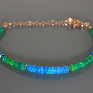 Pu&ograve; includere: Un braccialetto delicato realizzato con perline di opale verde e blu, collegate da una catena d'oro.