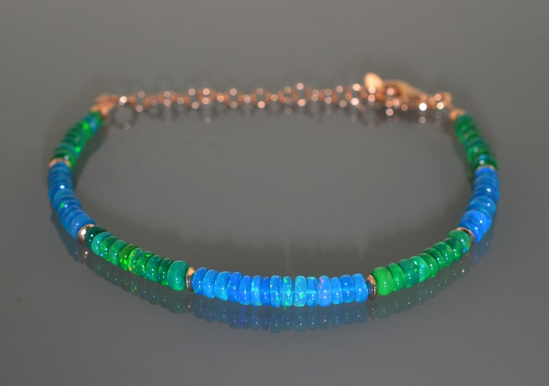 Pu&ograve; includere: Un braccialetto delicato realizzato con perline di opale verde e blu, collegate da una catena d'oro.