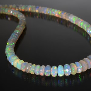 May include: A strand of iridescent opal beads, each bead is faceted and has a light green, blue, and orange shimmer.