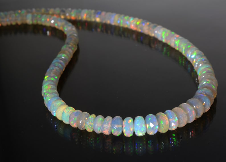 May include: A strand of iridescent opal beads, each bead is faceted and has a light green, blue, and orange shimmer.