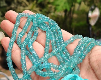 May include: A strand of light blue aquamarine beads, faceted and with a slightly irregular shape. The beads are strung on a thin cord and have a tassel at the end.