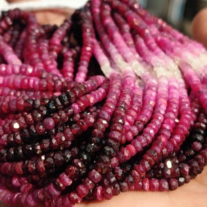 Könnte beinhalten: Eine Strähne aus Rubinperlen in verschiedenen Rosatönen und Rot. Die Perlen sind facettiert und haben eine glatte, polierte Oberfläche.