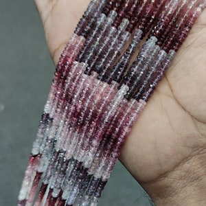 May include: A strand of pink, purple, and white gemstone beads. The beads are faceted and have a slightly irregular shape. The beads are strung on a clear thread.