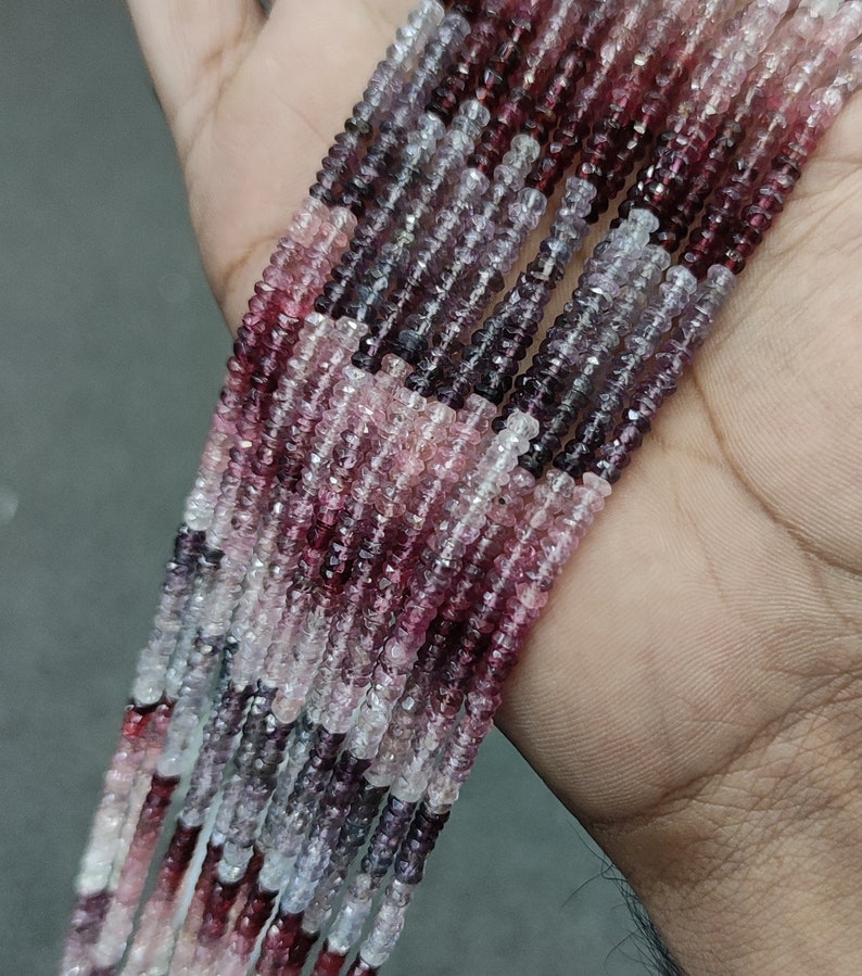 May include: A strand of pink, purple, and white gemstone beads. The beads are faceted and have a slightly irregular shape. The beads are strung on a clear thread.