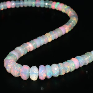 May include: A strand of iridescent opal beads in shades of white, pink, and blue. The beads are faceted and have a slightly irregular shape. The strand is approximately 18 inches long.
