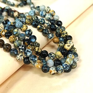 May include: A strand of blue, brown, and white agate beads. The beads are round and have a speckled pattern.
