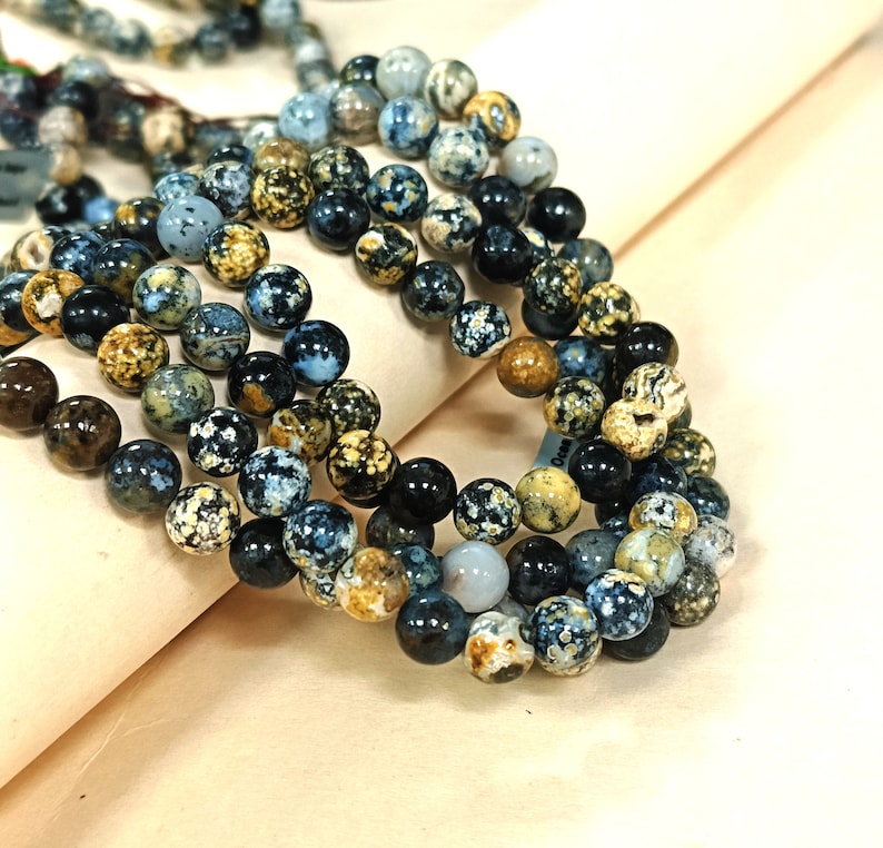 May include: A strand of blue, brown, and white agate beads. The beads are round and have a speckled pattern.