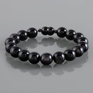 May include: A black beaded bracelet with a magnetic clasp. The beads are round and have a glossy finish. The bracelet is displayed on a reflective surface.