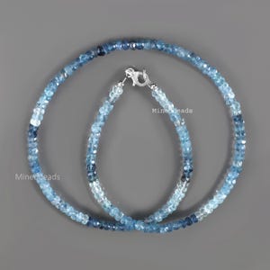May include: A necklace and a bracelet made of faceted blue gemstone beads in varying shades of light to dark blue. Both pieces feature a silver-toned lobster claw clasp. The text Minedbeads is visible on the image in two locations.