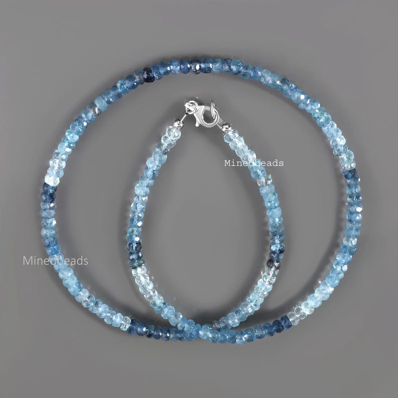 May include: A necklace and a bracelet made of faceted blue gemstone beads in varying shades of light to dark blue. Both pieces feature a silver-toned lobster claw clasp. The text Minedbeads is visible on the image in two locations.