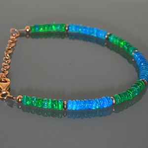 Pu&ograve; includere: Un braccialetto con perline di opale verde e blu con una chiusura dorata.