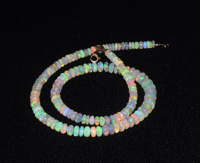 May include: A multi-colored opal bead necklace with a gold clasp. The necklace is made of small, round beads that are strung together on a thin gold chain.