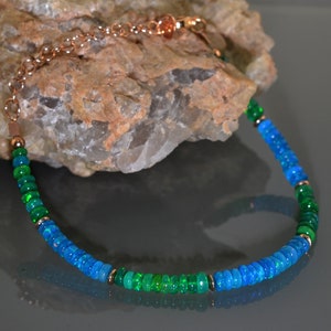 Pu&ograve; includere: Una collana realizzata con perline di opale verde e blu con una catena in rame.