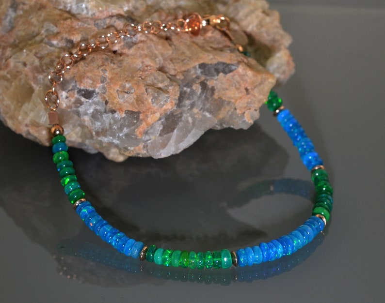 Pu&ograve; includere: Una collana realizzata con perline di opale verde e blu con una catena in rame.