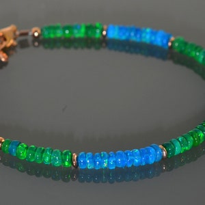 Pu&ograve; includere: Un braccialetto con perline di opale verde e blu con chiusura a catena dorata.
