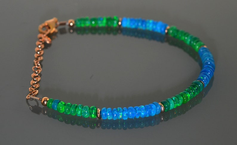 Pu&ograve; includere: Un braccialetto con perline di opale verde e blu con chiusura a catena dorata.