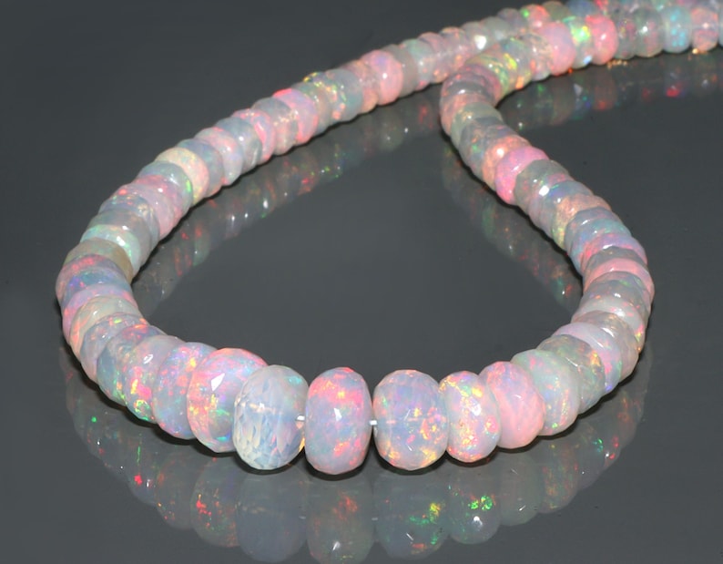 May include: A strand of iridescent opal beads in shades of white, pink, and blue. The beads are round and have a smooth, polished finish.