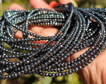 May include: A strand of black faceted gemstone beads. The beads are small and round, and they have a shiny, metallic finish.