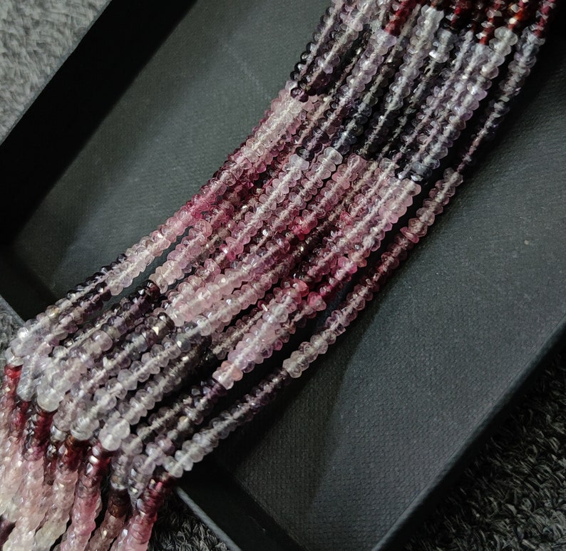 May include: A strand of pink, purple, and white gemstone beads. The beads are faceted and have a slightly irregular shape. The beads are strung on a clear thread.