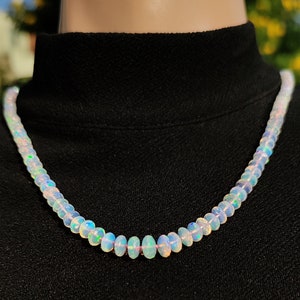 Pode incluir: Um colar de contas de opala branca com cores arco-&iacute;ris iridescentes. O colar &eacute; feito de pequenas contas de forma oval.