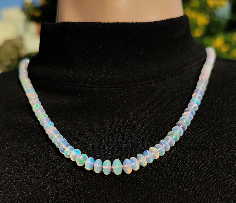 Pode incluir: Um colar de contas de opala branca com cores arco-&iacute;ris iridescentes. O colar &eacute; feito de pequenas contas de forma oval.