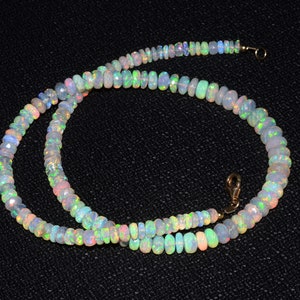 May include: A strand of iridescent opal beads, strung on a gold chain with a clasp. The beads are a pale white with flashes of green, blue, and pink.