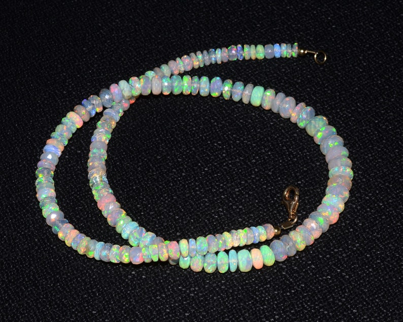 May include: A strand of iridescent opal beads, strung on a gold chain with a clasp. The beads are a pale white with flashes of green, blue, and pink.