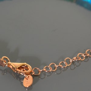 Pu&ograve; includere: Un braccialetto d'oro con chiusura a catena e perline di opale verde e blu.