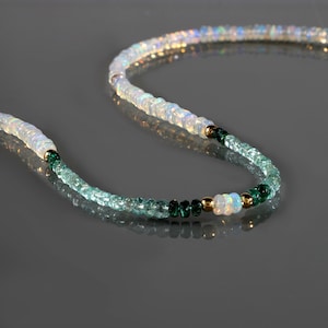 May include: A white opal and green gemstone beaded necklace. The necklace is made with small, round beads and features a gold accent.