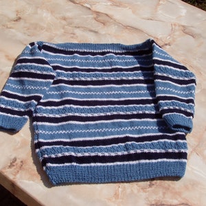 May include: A blue and white striped sweater with a wide neckline. The sweater is knitted with a textured pattern.
