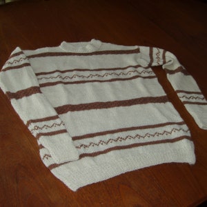 May include: A white and brown striped knitted jumper with a crew neck.