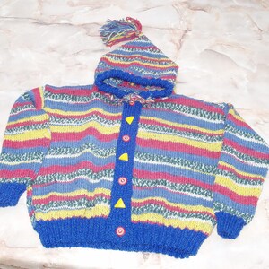 Peut inclure: Un pull en tricot rayé coloré avec un bonnet à capuche assorti. Le pull a une bordure bleue et des boutons jaunes.