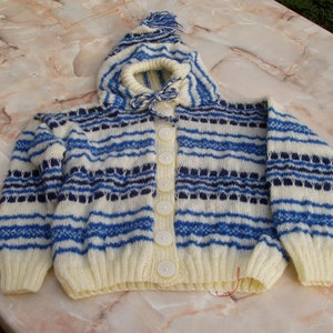 May include: A white knitted cardigan with blue and navy stripes, a hood, and button closure.